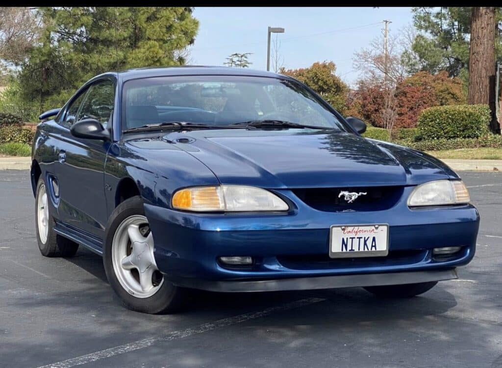 A Dark Blue 1996 Mustang GT in front of a beautiful park.