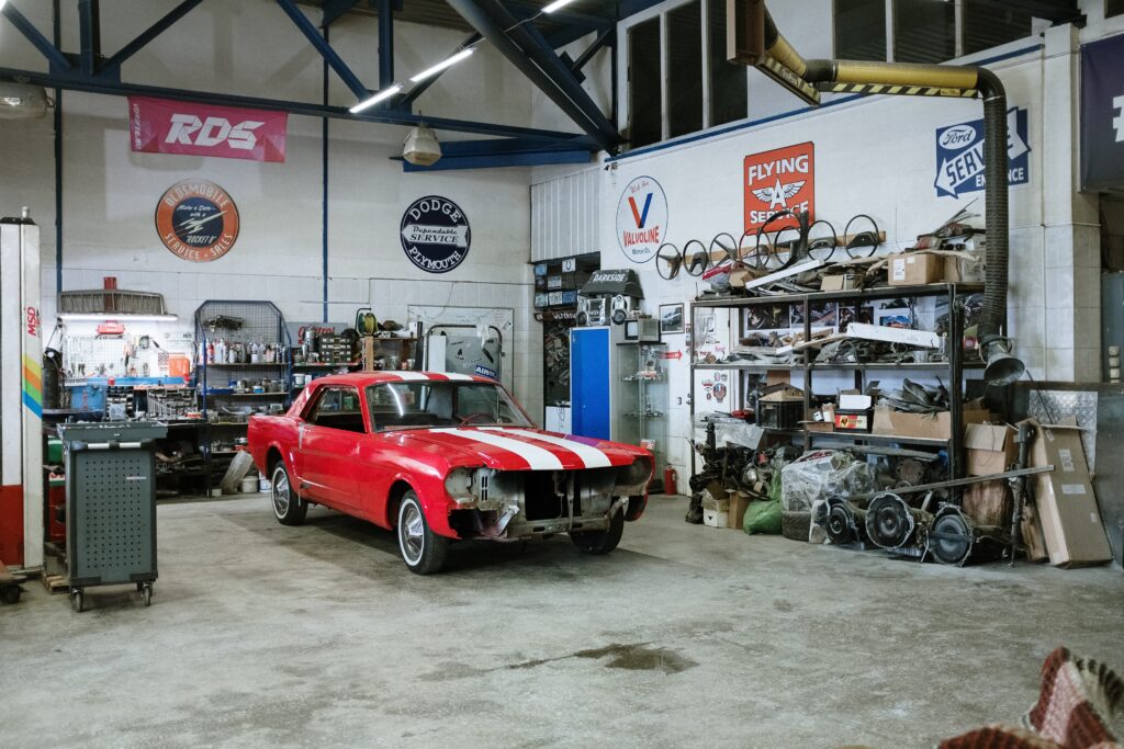 A classic car parked in a tool filled garage.