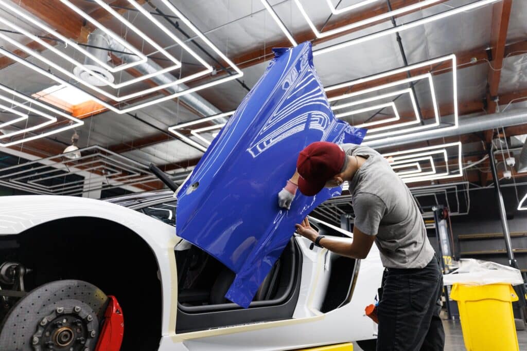 a man putting on a blue sticker on the car door