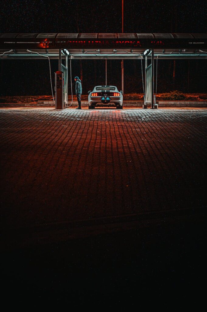 man standing next to a car at gas station