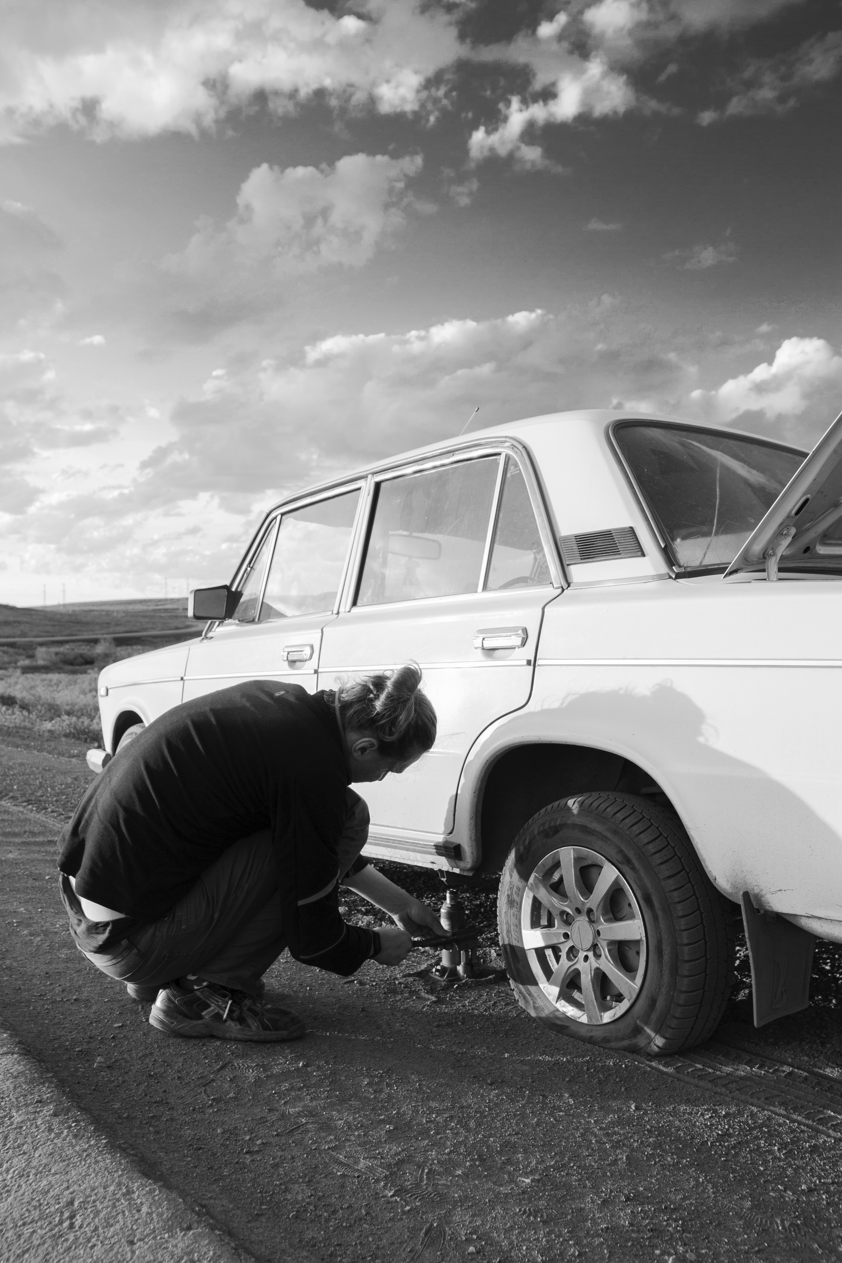 A man changing their tire with a floor jack.